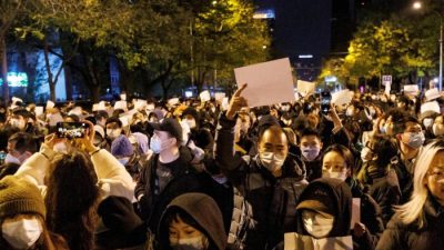 Люди держат белые листы бумаги в знак протеста против ограничений COVID-19 после панихиды в память о жертвах пожара в Урумчи, Пекин, Китай, 27 ноября 2022 года. (Thomas Peter/Reuters)
