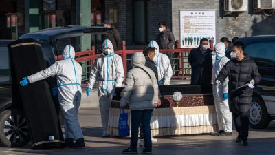 Рабочие в защитном снаряжении обрабатывают гроб в похоронном бюро «Дунцзяо», которое предназначено для смертельных случаев COVID-19, в Пекине 19 декабря 2022 года. (BloombergviaGettyImages)