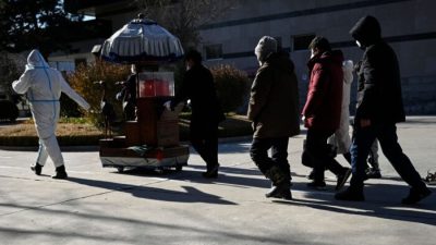 Члены семьи следуют за урной с прахом близкого человека в крематории в Пекине 22 декабря 2022 года. (STF/AFP via Getty Images)
