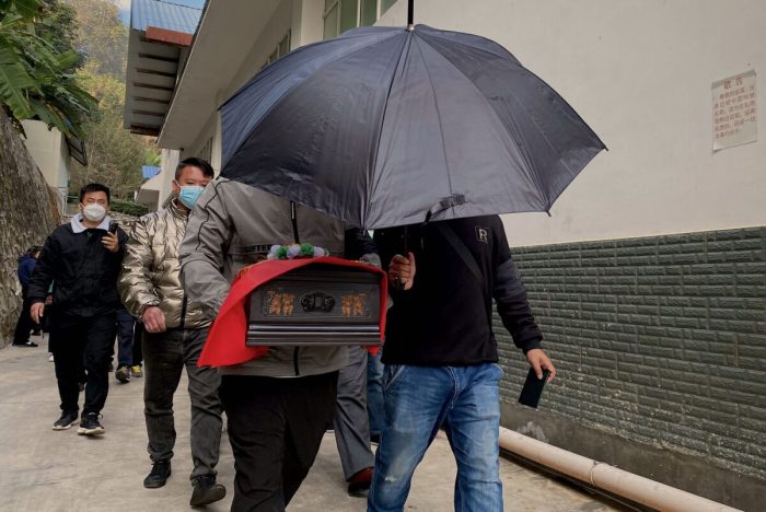 Родственники несут прах близкого человека, кремированного в похоронном бюро Сипсонгпанна Чжоу в городе Цзинхун, Сишуанбаньна-Дайский автономный округ, южная китайская провинция Юньнань, 10 января 2023 года. (Noel Celis/AFP via Getty Images)