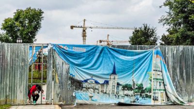 Женщина пролезает через дыру в рекламном щите в культурно-ориентированном туристическом городе Эвергранд в Ухане, провинция Хубэй, Китай, 18 октября 2021 года. (Getty Images)
