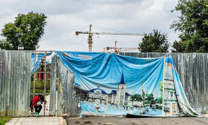 Женщина пролезает через дыру в рекламном щите в культурно-ориентированном туристическом городе Эвергранд в Ухане, провинция Хубэй, Китай, 18 октября 2021 года. (Getty Images)
