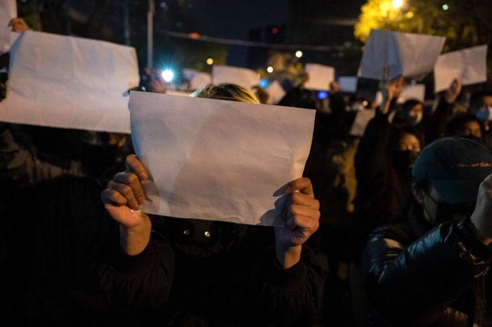 Протестующие держат белый лист бумаги во время марша протеста против строгих мер по борьбе с COVID-19 в Пекине 27 ноября 2022 года. (Kevin Frayer/Getty Images)