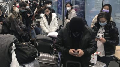 Путешественники, прибывающие в течение нескольких часов, ждут посадки в автобусы, чтобы отправиться в карантинные отели и объекты из аэропорта Гуанчжоу Байюнь в провинции Гуандун на юге Китая, 25 декабря 2022 года. (The Canadian Press/AP, Emily Wang Fujiyama)