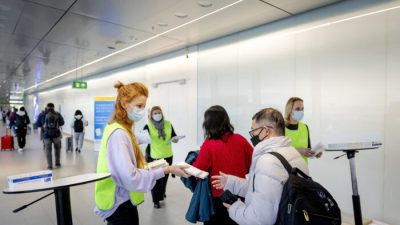 Сотрудник голландской муниципальной службы здравоохранения (GGD) раздаёт бесплатные наборы для самотестирования на COVID-19 путешественникам, прибывающим из Китая, в аэропорту Схипхол, Нидерланды, 4 января 2023 года. (Robin van Lonkhuijsen/ANP/AFP via Getty Images)

