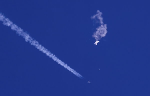 На этой фотографии, предоставленной Чадом Фишем, остатки большого воздушного шара дрейфуют над Атлантическим океаном, недалеко от побережья Южной Каролины, а под ним виден истребитель и его инверсионный след, 4 февраля 2023 года. (Chad Fish via AP)