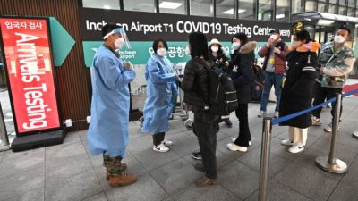 Медицинские работники сопровождают туристов из Китая перед центром тестирования COVID-19 в международном аэропорту Инчхон к западу от Сеула, 3 января 2023 года. (Jung Yeon-je/AFP via Getty Images)