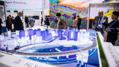 Посетители знакомятся с технологией 5G Smart City на стенде China Mobile на GSMA Mobile World Congress 2019 в Барселоне, Испания, 26 февраля 2019 года. В этом ежегодном конгрессе принимают участие некоторые из крупнейших мировых коммуникационных компаний, многие из которых представляют свои новейшие телефоны и носимые гаджеты, такие как складные экраны и внедрение беспроводных сетей 5G. (David Ramos/Getty Images)
