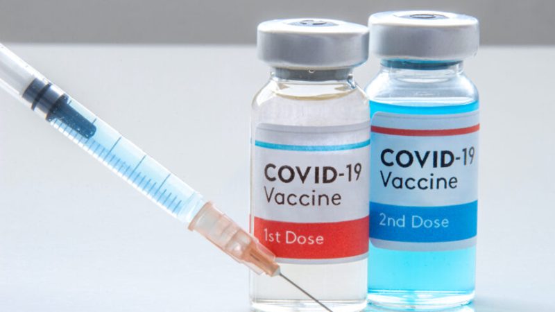 1st dosis and a 2nd dosis of covid-19 vaccine on a vial bottle and injection Syringe on a white table
