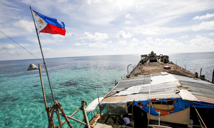 Филиппинский флаг развевается над BRP Sierra Madre, ветхим кораблём филиппинских ВМС, который в 1999 году сел на мель и с тех пор является филиппинским военным форпостом на спорной Второй отмели Томаса, являющейся частью островов Спратли, в Южно-Китайском море, 29 марта 2014 года. (Erik De Castro/Reuters)
