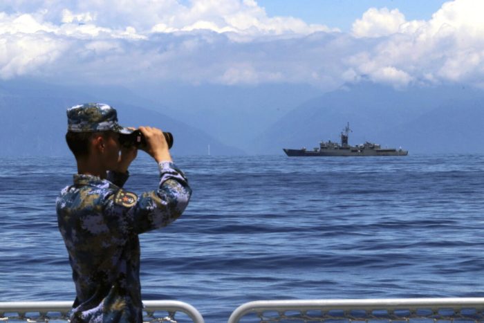 Боец Народно-освободительной армии смотрит в бинокль во время военных учений, а тайваньский фрегат «Лань Ян» виден на заднем плане 5 августа 2022 года. (Lin Jian/Xinhua via AP)