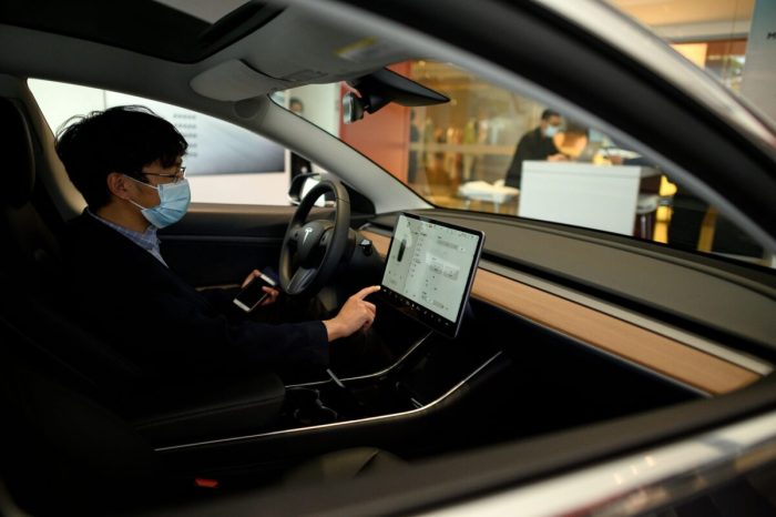 Клиент проверяет сенсорный экран приборной панели автомобиля Tesla, выставленного в выставочном зале в Пекине, 10 мая 2020 года. (Noel Celis/AFP via Getty Images)