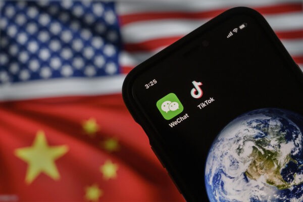 На экране мобильного телефона отображаются логотипы китайских приложений WeChat и TikTok на фоне монитора с изображением флагов США и Китая на интернет-странице, 22 сентября 2020 года в Пекине, Китай. (Kevin Frayer/Getty Images)