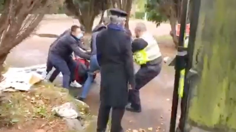 Видео показывает, как полицейский пытается спасти гонконгского демонстранта, которого избивают у китайского консульства в Манчестере, Англия, 16 октября 2022 года. (Screenshot via The Epoch Times)