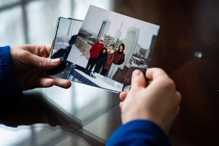 Steven Wang, Shen Yun principal dancer, looks at a photograph of himself with his mother and sisters, at his home in Sparrowbush, N.Y., on March 31, 2023. (Samira Bouaou/The Epoch Times)