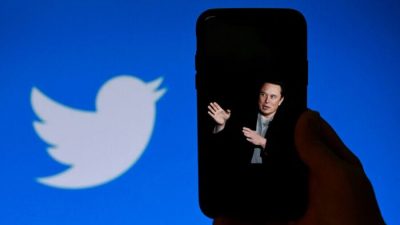 На экране телефона отображается фотография Илона Маска с логотипом Twitter на заднем плане в Вашингтоне 4 октября 2022 года. (Olivier Douliery/AFP via Getty Images)
