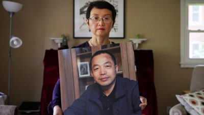 
Софи Луо Шэнчунь, жена заключённого в тюрьму китайского адвоката по правам человека Дин Цзяси, с его фотографией в её доме в Альфреде, Нью-Йорк, 28 июля 2022 года. (Brendan McDermid/Reuters)
