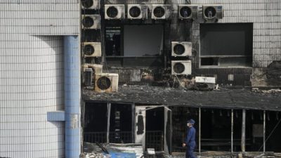 Следователь осматривает обгоревшую территорию после пожара в больнице в Пекине, 19 апреля 2023 года. (Andy Wong/AP Photo)
