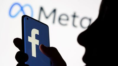 Женщина держит смартфон с логотипом Facebook перед отображаемой метой логотипа Facebook для ребрендинга на этой иллюстрации, сделанной 28 октября 2021 года. (Dado Ruvic/Illustration/Reuters)