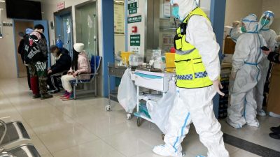 Сотрудник службы безопасности в защитном костюме наблюдает за тем, как медицинские работники обслуживают пациентов в больнице Тунцзи для больных COVID-19, Ухань, провинция Хубэй, Китай, 1 января 2023 года. (Reuters)