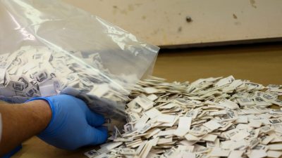 Работник Управления по борьбе с наркотиками (DEA) высыпает 2500 упаковок с фентанилом на стол для тестирования в Северо-восточной региональной лаборатории DEA 8 октября 2019 года в Нью-Йорке. (Don Emmert/AFP via Getty Images)
