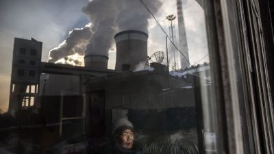 Жительница Китая смотрит в окно своего дома рядом с угольной электростанцией в провинции Шаньси, Китай, 26 ноября 2015 года. (Kevin Frayer/Getty Images)