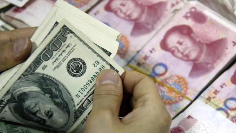 Доллары рядом со стопками банкнот в 100 юаней в банке в Хуайбэй, провинция Аньхой на востоке Китая, 24 сентября 2013 года. (STR/AFP via Getty Images)