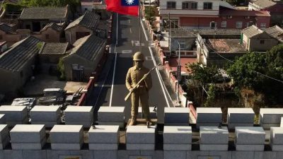 Статуя солдата и тайваньский флаг на вершине арки, построенной в память о битве при Гунингтоу в 1949 году на тайваньских островах Киньмэнь 20 октября 2020 года. Острова Киньмэнь находятся всего в 2 милях (3,2 км) от побережья материкового Китая (на заднем плане) в Тайваньском проливе. (Sam Yeh/AFP via Getty Images)