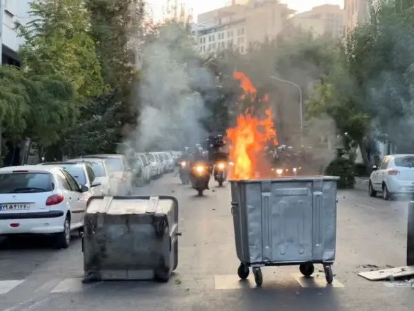 Мусорный бак горит, когда полиция прибывает на акцию протеста в связи со смертью молодой женщины, которая была задержана за нарушение консервативного дресс-кода страны, в центре Тегерана, Иран, 20 сентября 2022 года. (AP Photo)