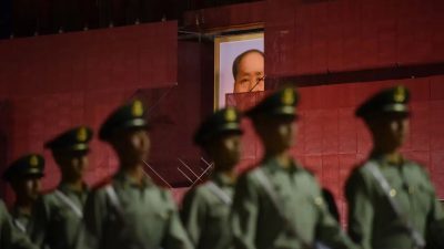 На этой фотографии, сделанной 18 мая 2019 года, запечатлены сотрудники военизированной полиции, марширующие мимо портрета покойного коммунистического лидера Мао Цзэдуна на воротах Тяньаньмэнь во время ремонтных работ в Пекине. (Photo by GREG BAKER / AFP) (Photo by GREG BAKER/AFP via Getty Images)