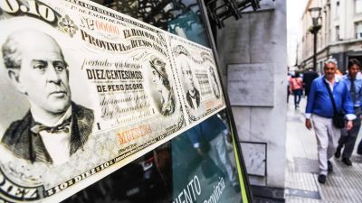 Люди проходят мимо отделения банка, украшенного изображениями старых банкнот аргентинского песо, в Буэнос-Айресе, Аргентина, 26 сентября 2018 года. Инфляция в Аргентине в годовом исчислении достигла 142% в неделю выборов. (Eitan Abramovich/AFP via Getty Images)
