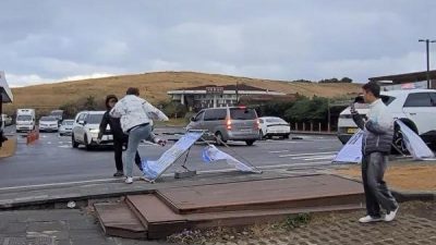 Китаец (в центре) разрушает информационные стенды Фалуньгун, в то время как его сообщник (справа) снимает весь процесс нападения на Санрайз-Пик на южном острове Чеджудо в Южной Корее 17 декабря 2023 года. (Courtesy of Kim Jung Gon)