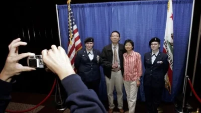 Новоиспечённые граждане США фотографируются с членами караула младшего подразделения ROTC вооружённых сил США после принятия присяги на гражданство США во время церемонии натурализации в Сан-Франциско, 23 мая 2006. (Justin Sullivan/Getty Images)
