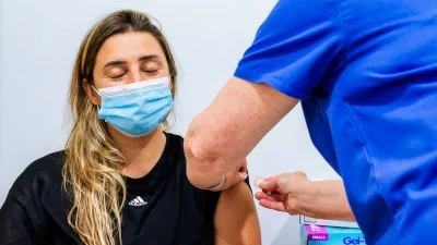 Женщина после введения вакцины против COVID-19 в клинике Sydney Road Family Medical Practice в Балгоулах в Сиднее, Австралия, 10 января 2022 г. (Jenny Evans/Getty Images)