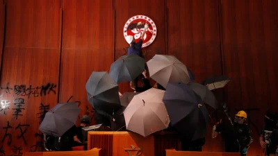 Протестующие закрашивают логотип Гонконга в Законодательном совете в знак протеста против законопроекта об экстрадиции в Гонконге, 1 июля 2019 года. (Vincent Yu/AP Photo)