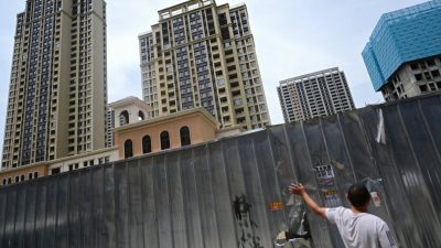 Мужчина, стоящий у шлагбаума в комплексе недостроенных жилых домов в городе Синьчжэн в Чжэнчжоу, центральная провинция Хэнань в Китае, 20 июня 2023 года. (Pedro PARDO / AFP)