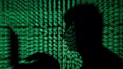 На иллюстрации, созданной 13 мая 2017 года, мужчина держит портативный компьютер, на фоне киберкода. (Kacper Pempel/Reuters)