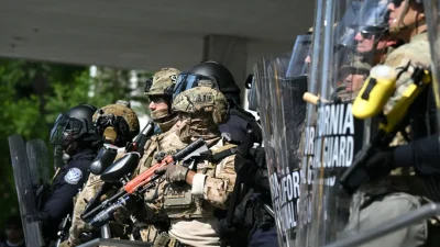 Полицейские стоят в окружении членов Национальной гвардии Калифорнии у Федерального здания во время акции протеста в ответ на федеральные иммиграционные операции в Лос-Анджелесе, 9 июня 2025 года. (Ronaldo Schemidt/AFP via Getty Images)