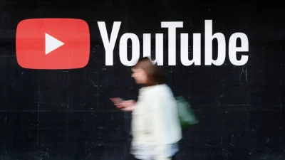 Молодая женщина со смартфоном проходит мимо рекламного щита YouTube в Берлине, Германия, 27 сентября 2019 года. (Sean Gallup/Getty Images)