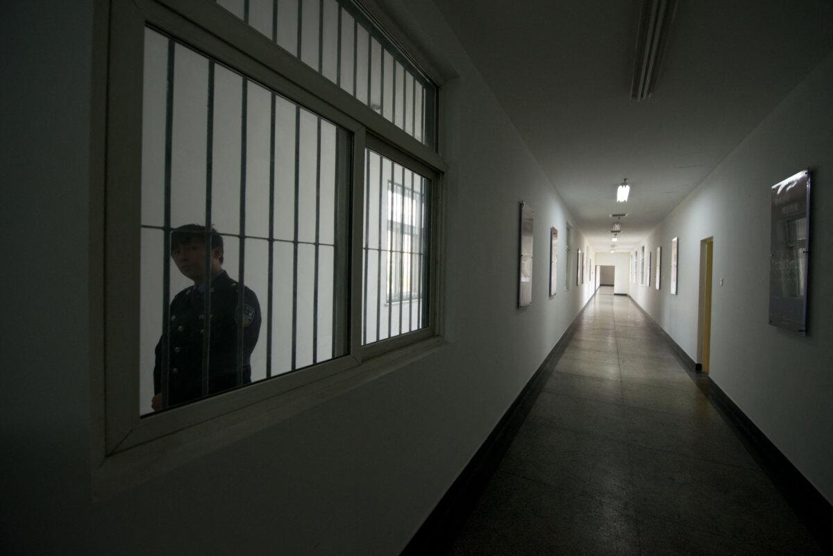 Охранник смотрит в окно коридора в центре заключения в Пекине 25 октября 2012 года. (Ed Jones/AFP via Getty Images)