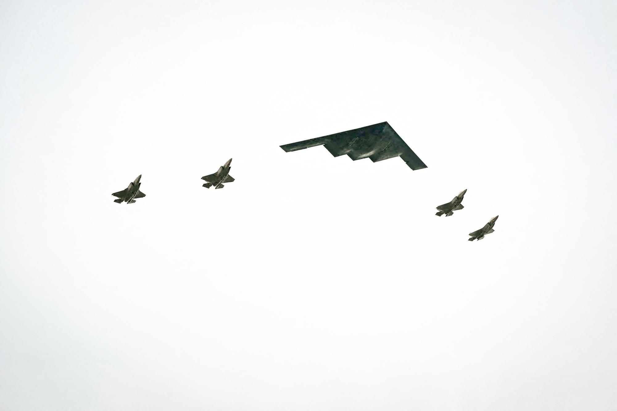 Бомбардировщик B-2 и четыре истребителя F-35 пролетают над головой, пока президент США Дональд Трамп приветствует президента России Владимира Путина на взлётно-посадочной полосе объединённой базы Элмендорф-Ричардсон в Анкоридже, Аляска, 15 августа 2025 года. (Andrew Caballero-Reynolds/AFP via Getty Images)