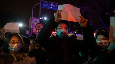 Протестующие поднимают белый лист бумаги в знак протеста против цензуры во время акции против строгих мер по борьбе с COVID-19, в Пекине, 27 ноября 2022 года. (Kevin Frayer/Getty Images)