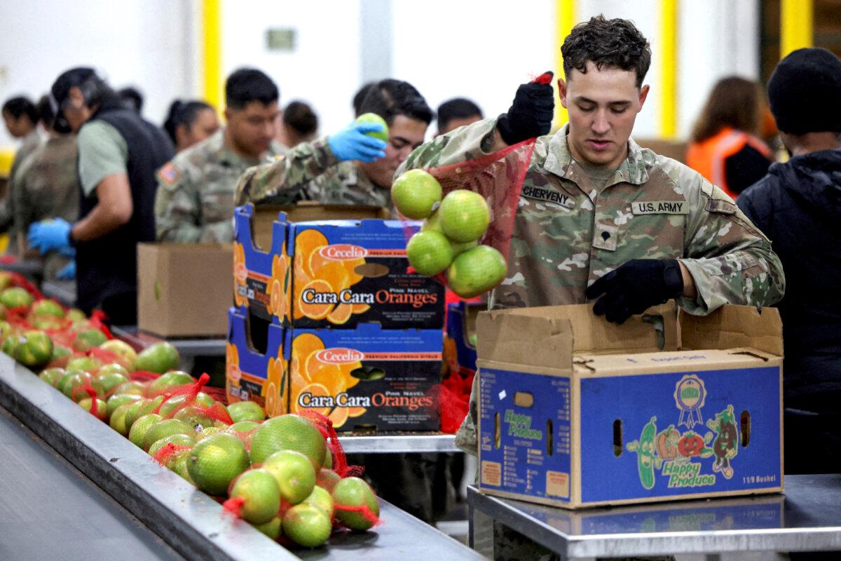 Военнослужащий Национальной гвардии упаковывает продукты в Региональном продовольственном банке Лос-Анджелеса. Почти 42 миллионам американцев грозит прекращение выплат по Программе дополнительной продовольственной помощи (SNAP), известной как продовольственные талоны, из-за второй по продолжительности приостановки работы правительства США. Лос-Анджелес, 29 октября 2025 г. (Daniel Cole/Reuters)