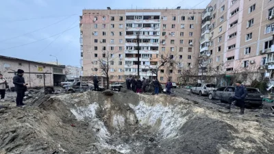 Люди стоят у воронки, образовавшейся в результате авиаудара в Запорожье 28 января 2026 года. (Darya Nazarova/AFP via Getty Images)