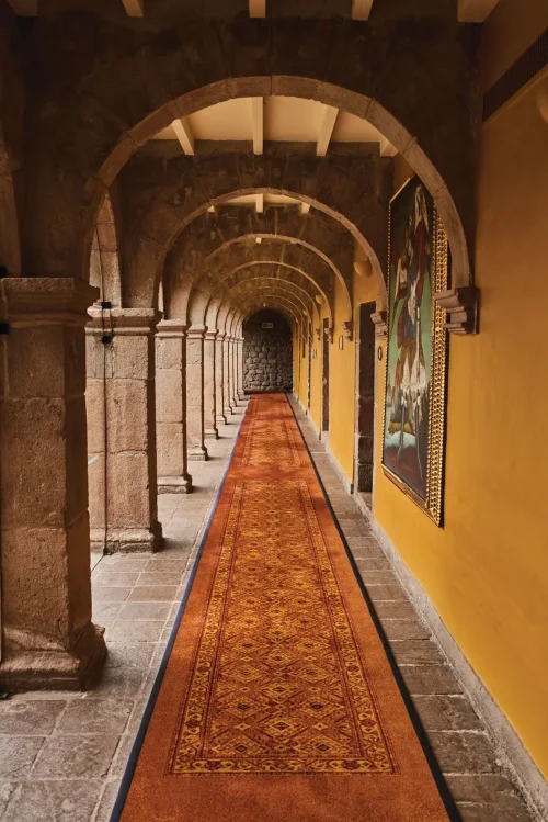 Крытая каменная дорожка (клуатр) отеля Monasterio с картинами XVIII века на стенах.