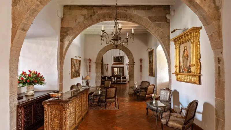 Ресторан отеля Belmond Monasterio с высокими каменными арками и антикварной мебелью.