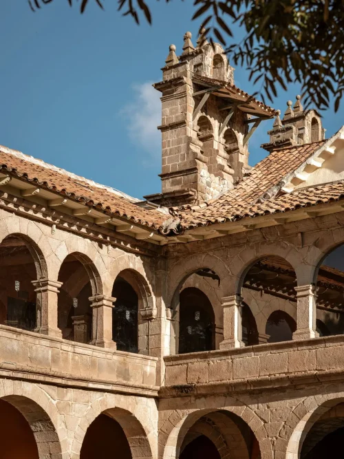 Деталь архитектуры отеля Monasterio: каменные арки второго этажа и крыша из терракотовой плитки.