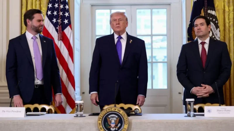 Дональд Трамп стоит за трибуной в окружении Джей-Ди Вэнса и Марко Рубио на фоне американских флагов.