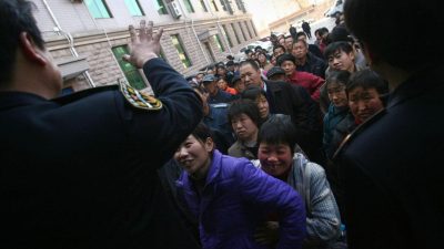 Сотрудники Пекинского бюро труда и социального обеспечения сдерживают рабочих-мигрантов, желающих получить задолженность по зарплате. 9 февраля 2007 года, Пекин, Китай.
