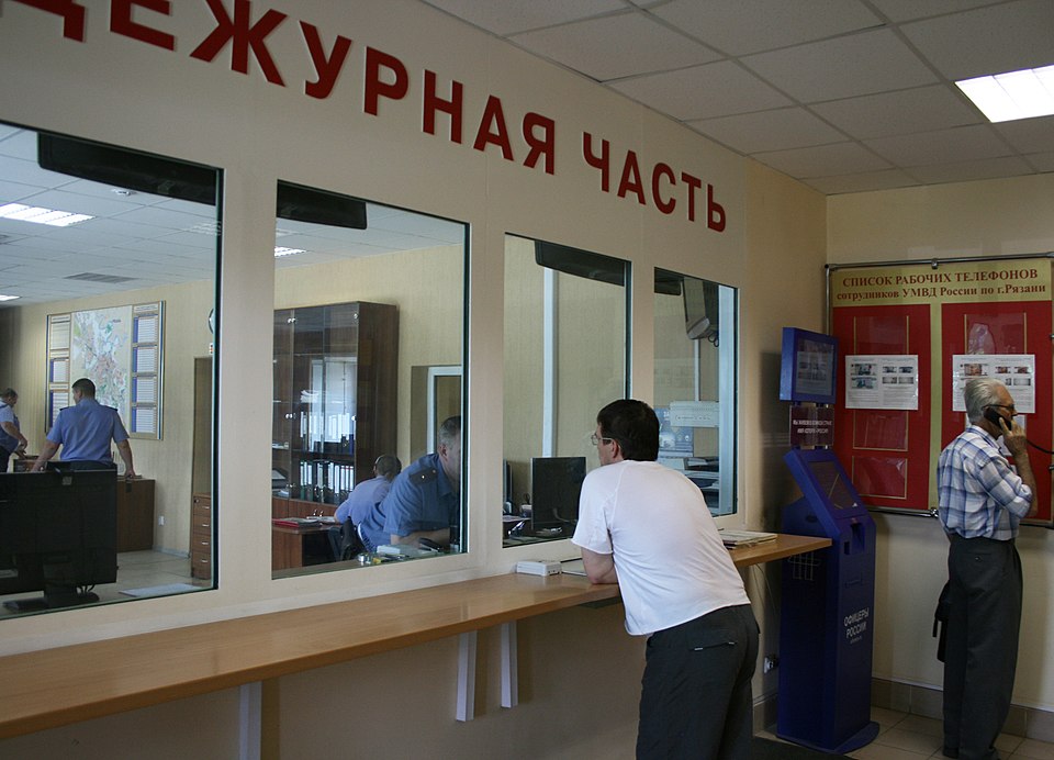Сотрудник полиции принимает заявление от гражданина за столом